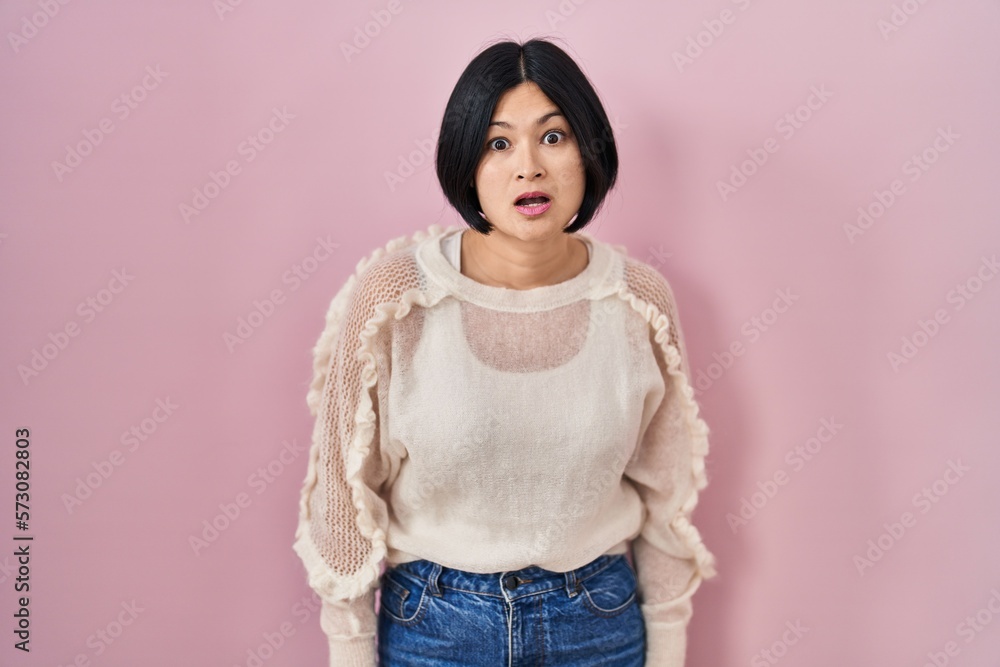 Sticker young asian woman standing over pink background afraid and shocked with surprise expression, fear an