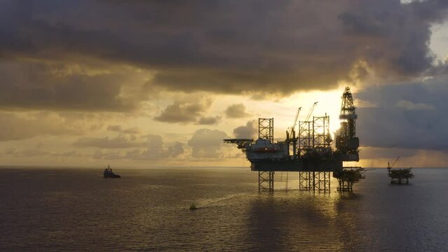 Jack up drilling rig and production platform in the middle of the ocean at sunrise time
