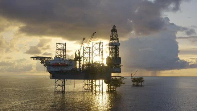 Jack up drilling rig and production platform in the middle of the ocean at sunrise time
