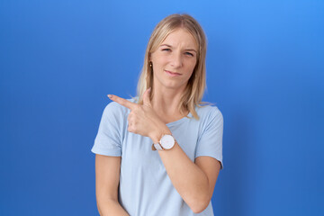 Young caucasian woman wearing casual blue t shirt pointing aside worried and nervous with forefinger, concerned and surprised expression