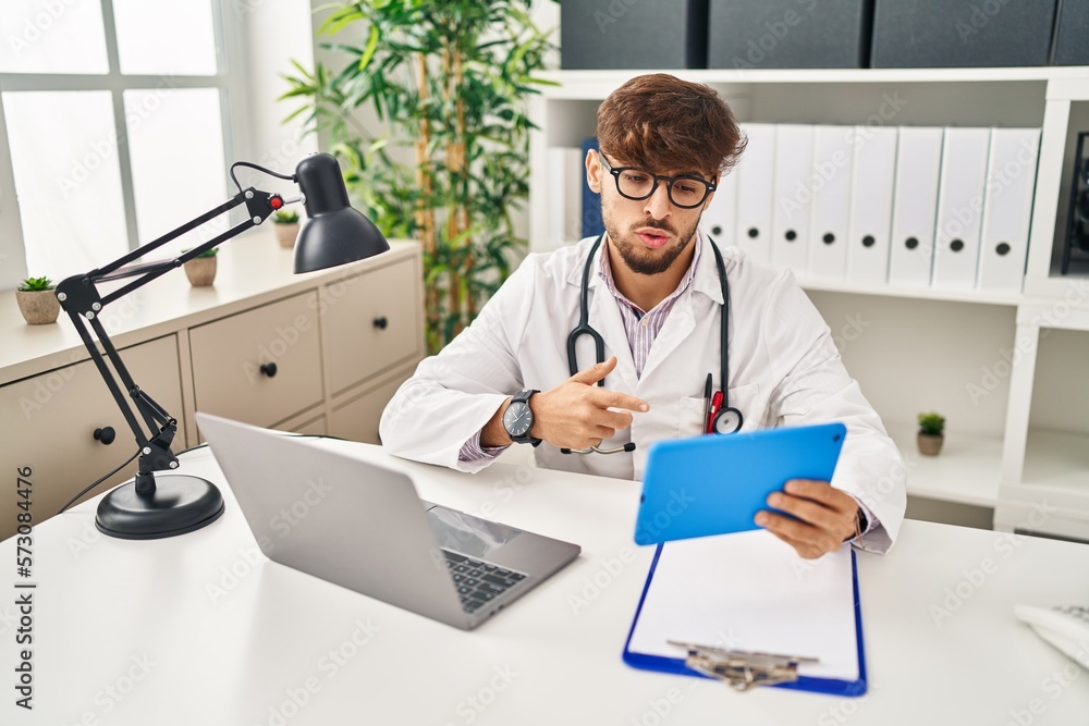 Sticker Young arab man wearing doctor uniform having video call at clinic