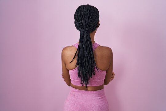 African american woman with braids wearing sportswear over pink background standing backwards looking away with crossed arms