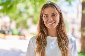 Young blonde girl smiling confident standing at park