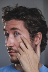 Fototapeta premium Handsome young man applying foundation to his face