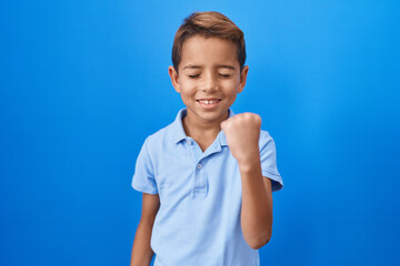 Little hispanic boy wearing casual blue t shirt celebrating surprised and amazed for success with arms raised and eyes closed