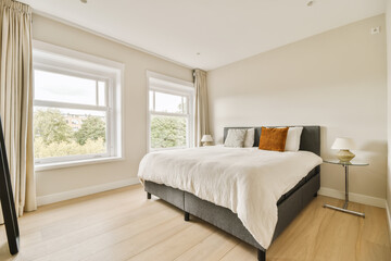 a bedroom with hardwood flooring and large windows overlooking the cityscapet is in front of the bed - Powered by Adobe