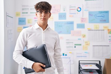 Young hispanic teenager business worker smiling confident holding binder at office