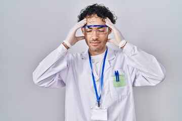 Hispanic man working at scientist laboratory with hand on head, headache because stress. suffering migraine.