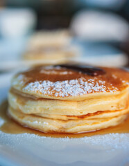 Sweet pancakes with maple syrup and jam on a plate, traditional breakfast dessert