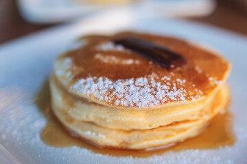 Sweet pancakes with maple syrup and jam on a plate, traditional breakfast dessert