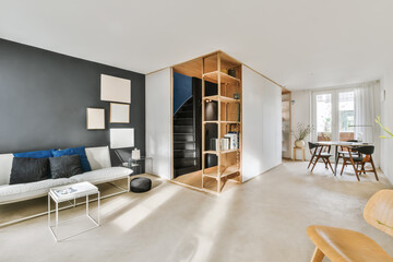 a living room with black walls and white furniture, including a wooden bookcase on the left hand -...