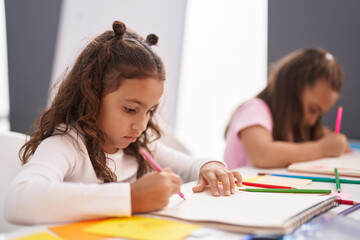 Two kids preschool students sitting on table drawing on paper at classroom