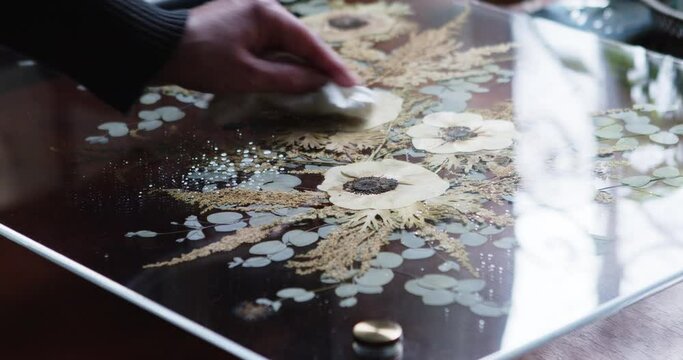 Close-up of woman's hand cleaning the surface of her pressed wedding bouquet between plexiglass. 4K ProRes 422 HQ DCI 4096 x 2160.  Shot on Blackmagic Cinema Camera 6K Pro handheld, natural light  