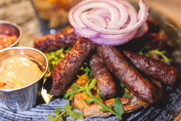 Cevapi on a plate, traditional balkan dish, grilled minced beef meat, Cevapcici, with onion and french fries served in restaraunt in Kotor, Montenegro, balkan cuisine