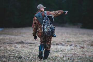 A process of hunting during spring hunting season, process of duck hunting, group of hunters in camouflage clothing holding shotgun rifle and reloading the ammo in the autumn swamp forest