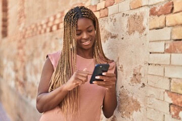 African american woman smiling confident using smartphone over isolated stone background