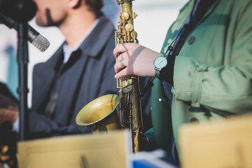 Concert view of a female saxophonist, professional saxophone player with vocalist and musical during jazz band orchestra performing, young girl musician