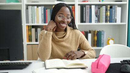 African woman reading a book sitting on desk at library university