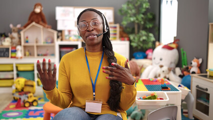 African woman preschool teacher on a video call using headset at kindergarten