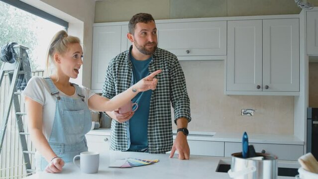 Couple renovating kitchen at home looking at paint colour swatches on coffee break - shot in slow motion