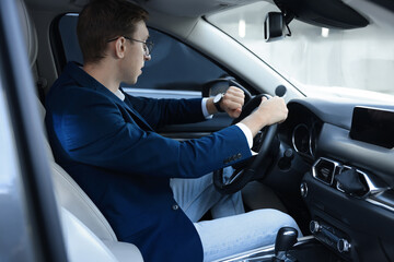 Young man checking time in car. Being late