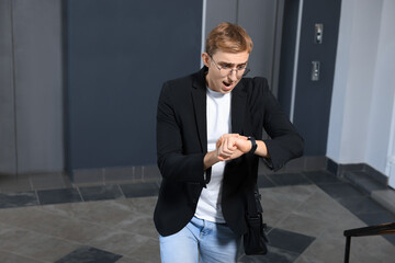 Emotional young man checking time in office. Being late