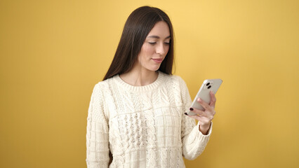 Young beautiful hispanic woman using smartphone with serious expression over isolated yellow background