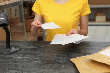 Post office worker with envelopes at counter indoors, closeup