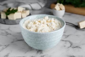 Delicious tofu cream cheese in bowl on white marble table, closeup