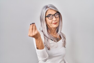 Middle age woman with grey hair standing over white background doing italian gesture with hand and fingers confident expression