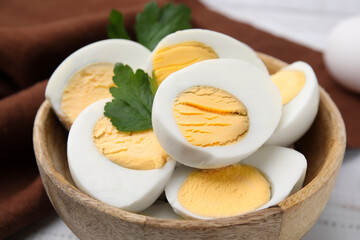 Wooden bowl with fresh hard boiled eggs and parsley on table, closeup