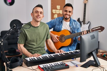 Two men musicians playing piano and classical guitar at music studio