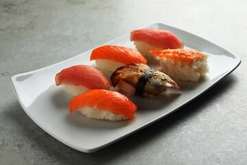 Plate with delicious nigiri sushi on grey table