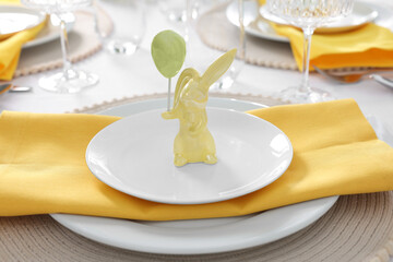Festive table setting with cutlery, plate and bunny figure, closeup. Easter celebration