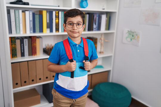 Adorable hispanic boy student smiling confident standing at library school