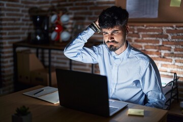 Young hispanic man with beard working at the office at night confuse and wonder about question....