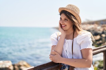 Young hispanic woman tourist smiling confident leaning on balustrade at seaside