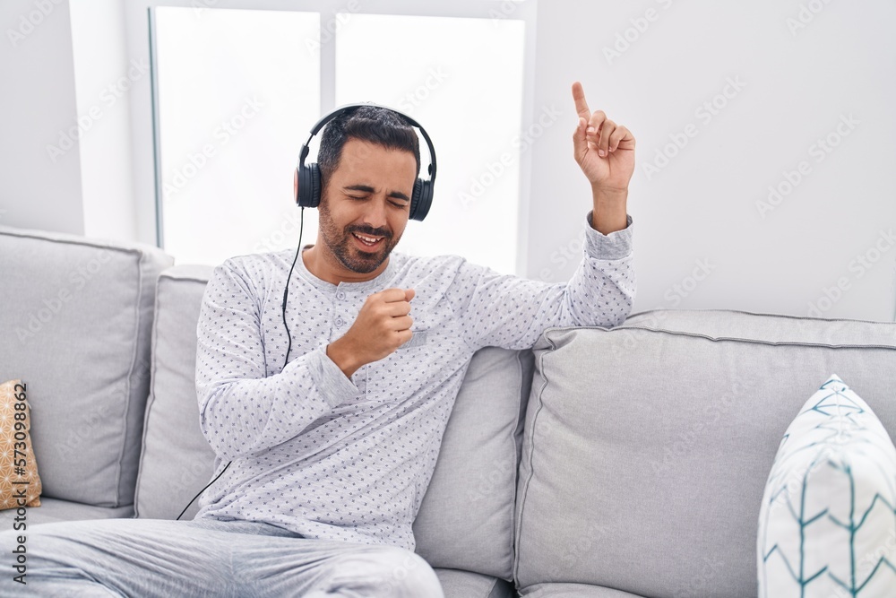 Sticker young hispanic man listening to music and singing son at home