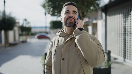 Young hispanic man smiling confident talking on smartphone at street