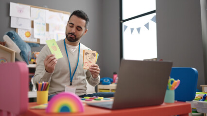 Young hispanic man working as teacher teaching online words lesson at kindergarten