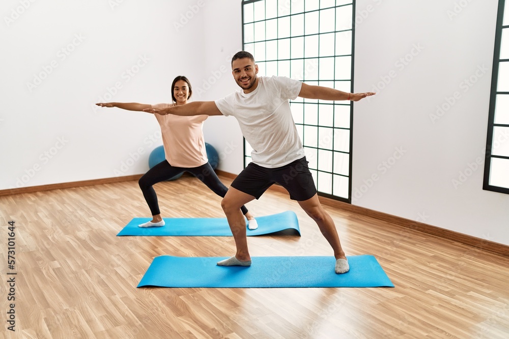 Wall mural latin man and woman couple smiling confident training yoga at sport center