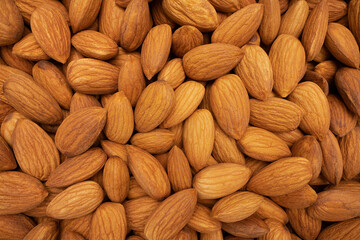 Beautiful pile of big raw peeled almonds laying in the background. which is a view close to the object. Shot with a sharp macro lens. Healthy food concept.