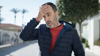 Middle age man standing with worried expression at street