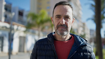 Middle age man standing with serious expression at street