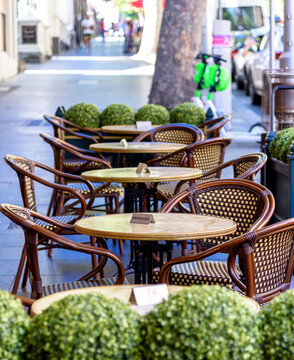 A row of reserved chairs and tables at an outdoor street cafe on Collins Street, Melbourne, Australia