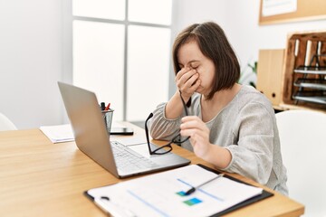 Brunette woman with down syndrome working tired at business office