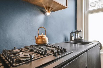 a kitchen with a tea kettle on the stove top and blue walls in the photo is taken from behind it