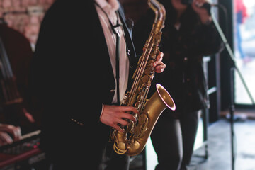 Concert view of saxophonist, a saxophone sax player with vocalist and musical band during jazz orchestra show performing music on a stage in the scene lights