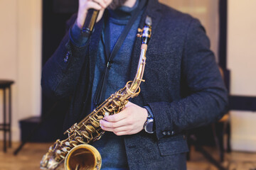 Concert view of saxophonist, a saxophone sax player with vocalist and musical band during jazz orchestra show performing music on a stage in the scene lights
