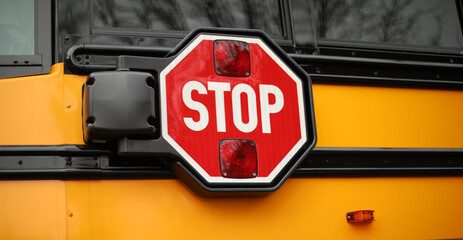 yellow school bus in public with stop sign showing 